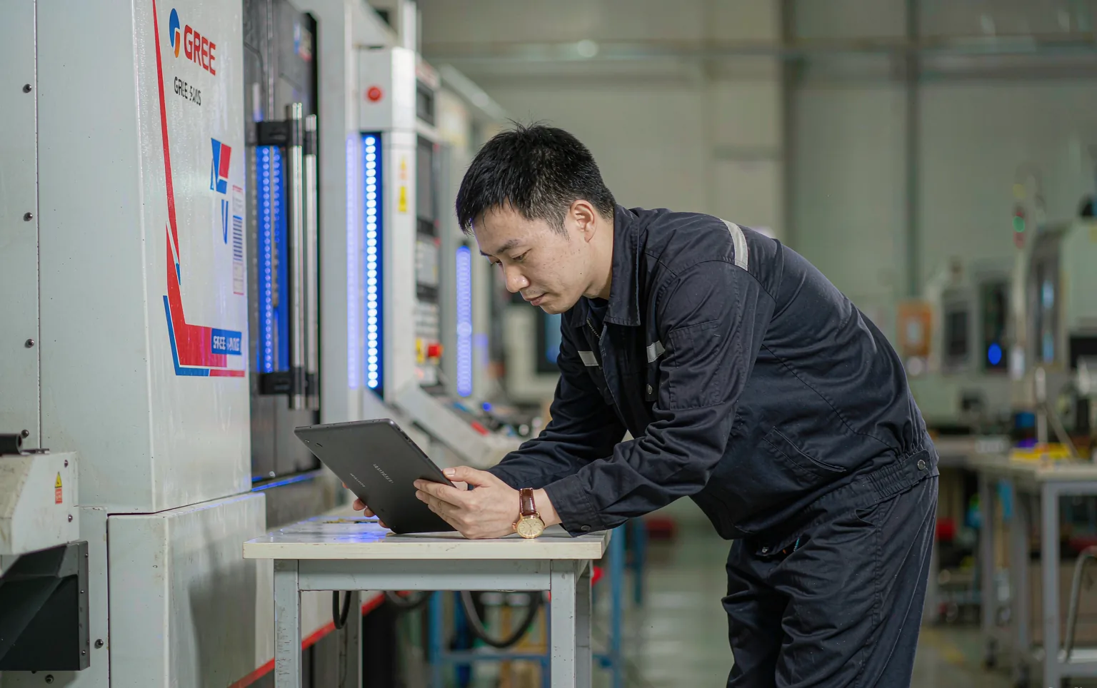 Engineer reviewing a Gree five-axis CNC machining center quotation on a tablet inside a modern machine shop